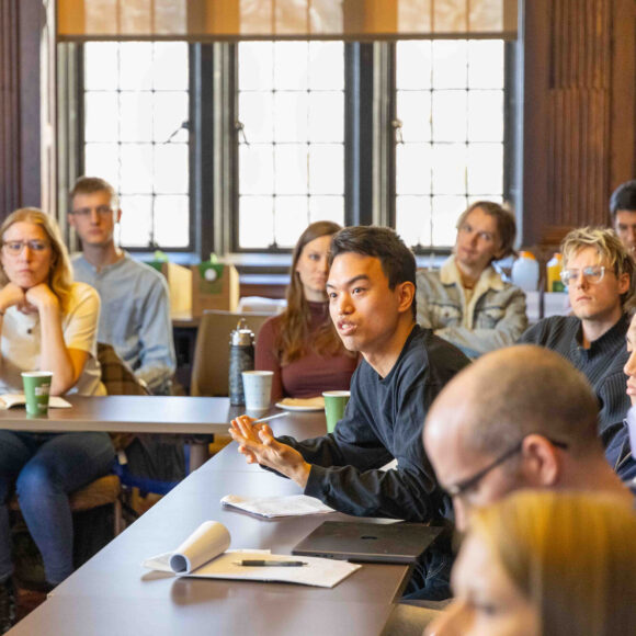 Seated students asks a questions during an Inequality Workshop.